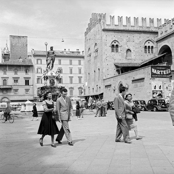 Some people walking on Piazza del Nettuno. behind them, the Palazzo Re Enzo. Bologna, May 1955 (Photo by Mario De Biasi/Mondadori Portfolio/Mondadori via Getty Images)
