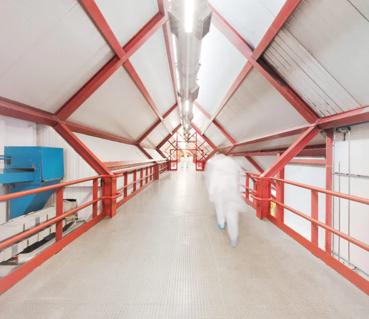 Long corridor in industrial setting, with a person in a white lab coat