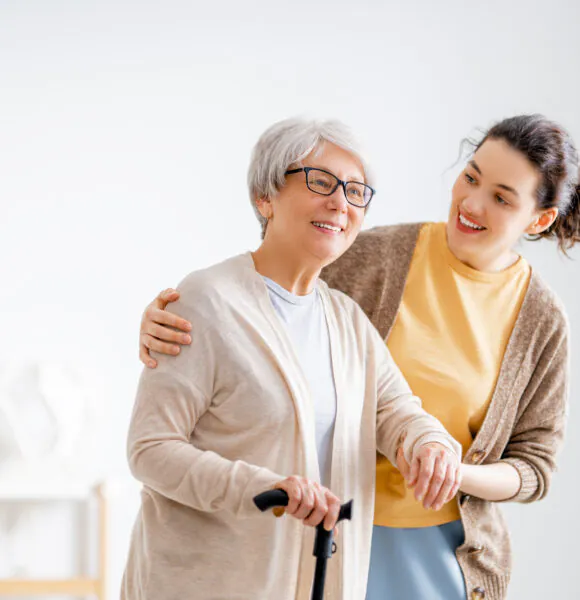 Happy patient and caregiver spending time together. Senior woman holding cane.