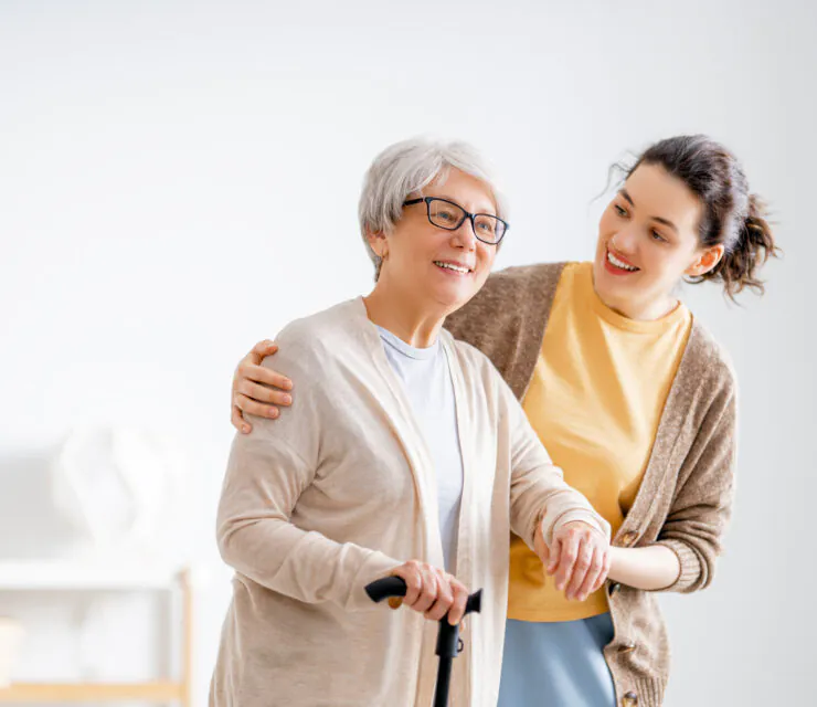 Happy patient and caregiver spending time together. Senior woman holding cane.