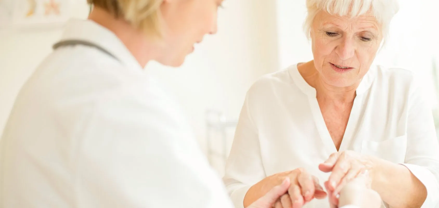 Female doctor examining senior patient's hand