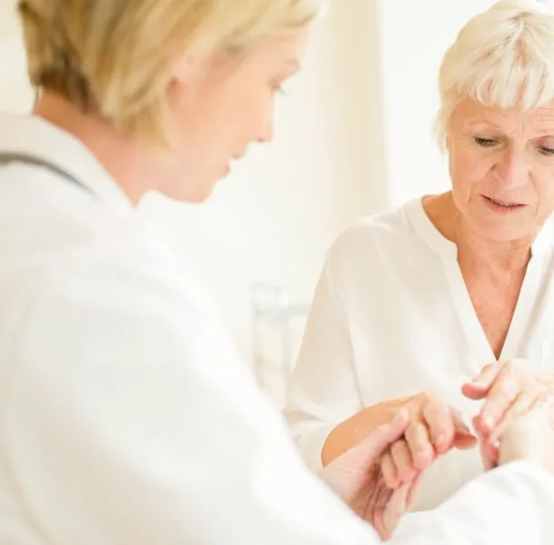 Female doctor examining senior patient's hand
